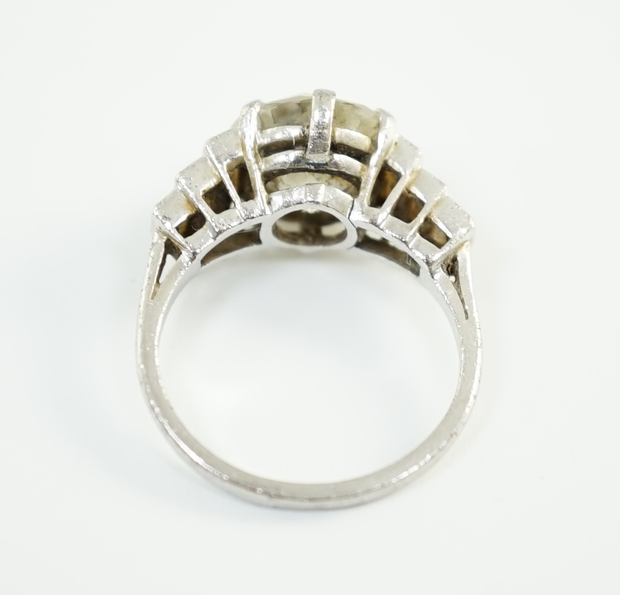 An Art Deco platinum and single stone diamond set ring, with six stone graduated baguette cut diamond set shoulders